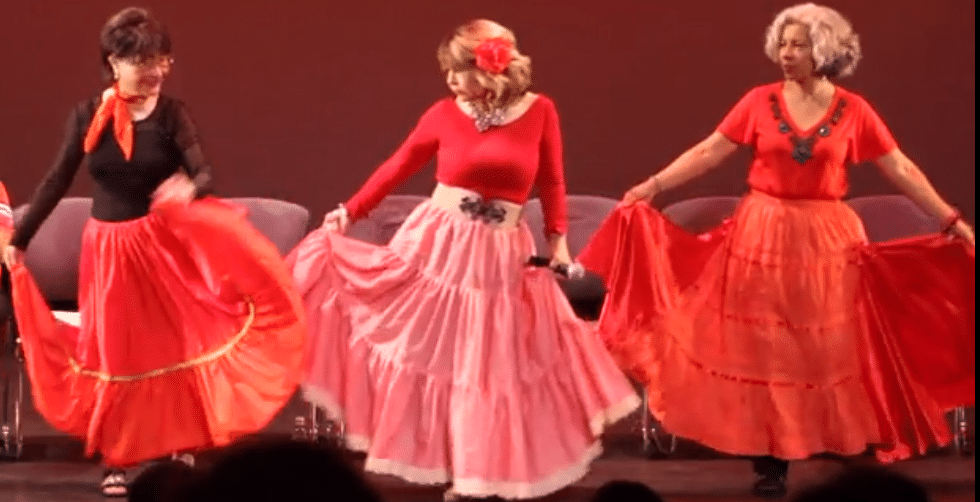 A trio of women in red dresses dancing