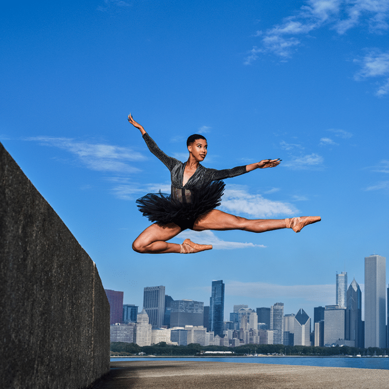 Photo of dancer leaping with city skyline in the background
