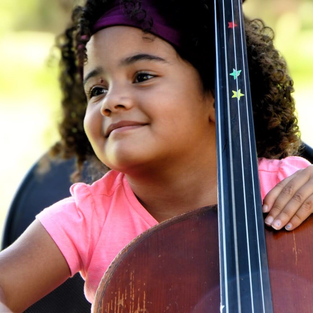 A smiling little girl holding a bass