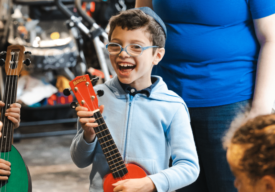 Child holding a small guitar, smiling